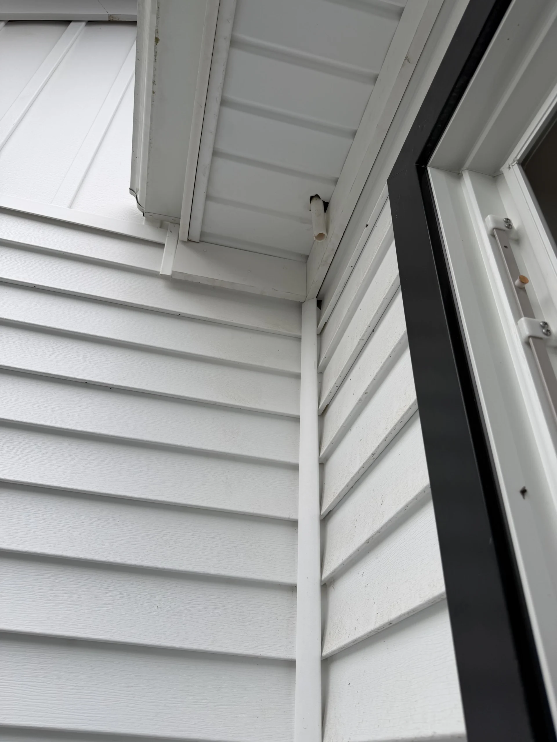 Short white pipe extending through the soffit above an exterior roof area